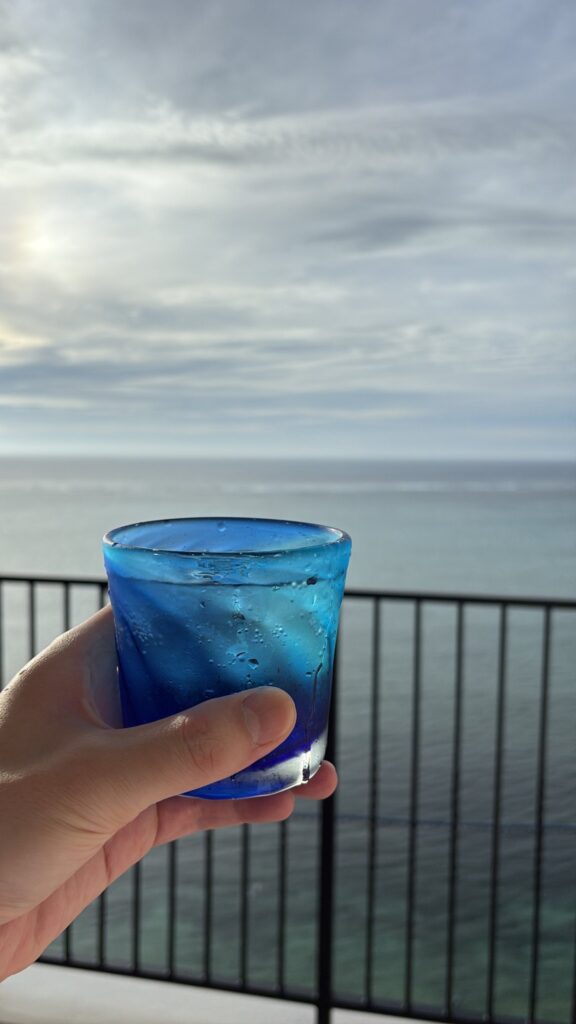 バルコニーで海を眺めながら飲む青いグラスの泡盛