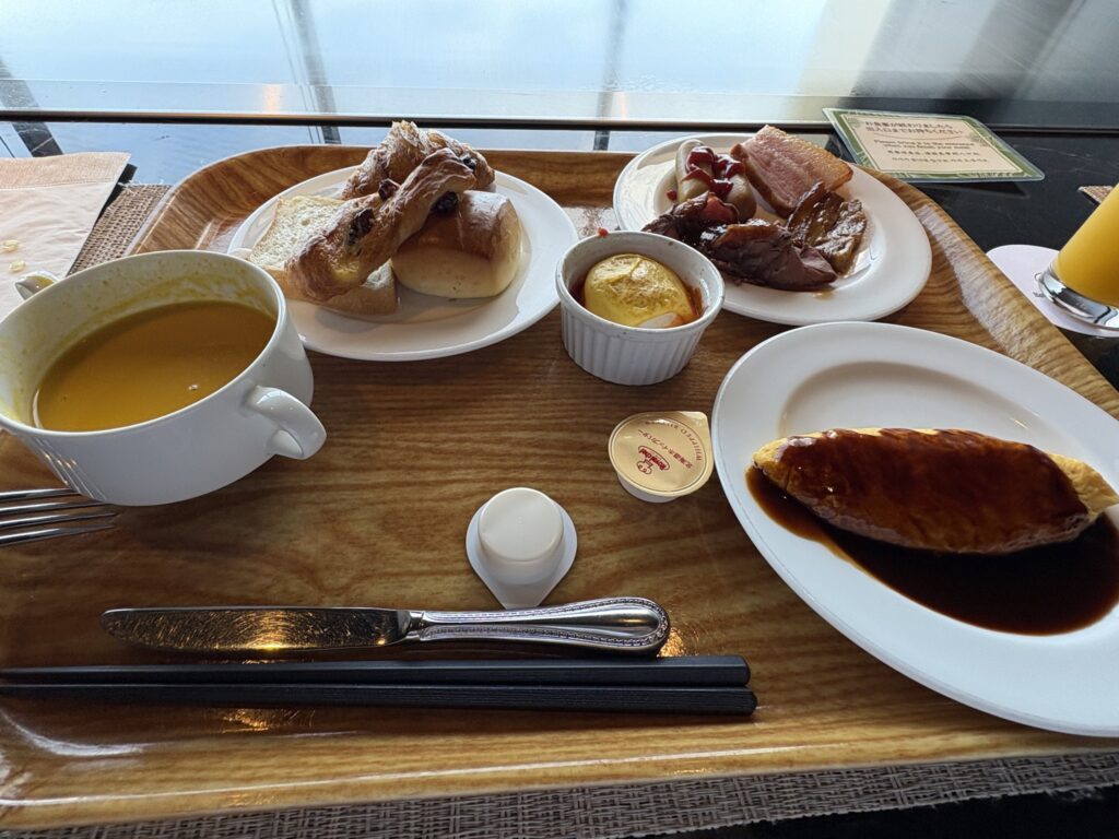 ソースのかかったオムレツとパン、スープの朝食プレート